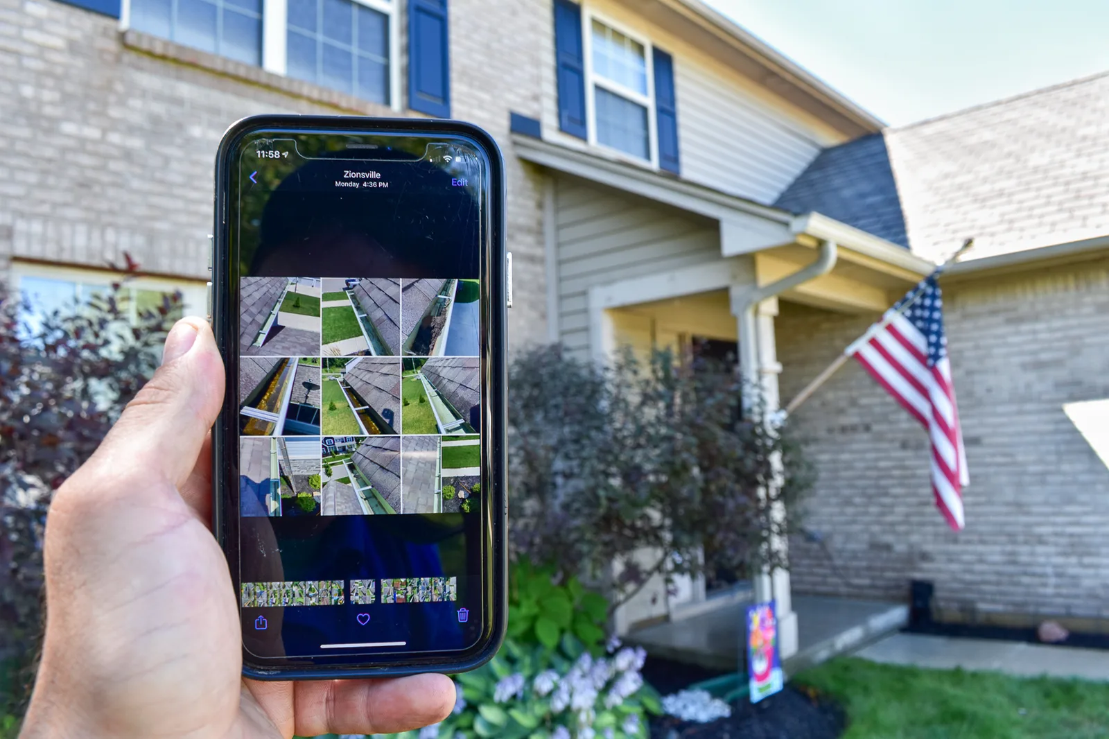 Hand holding phone showing grid of gutter cleaning verification photos in front of customer home