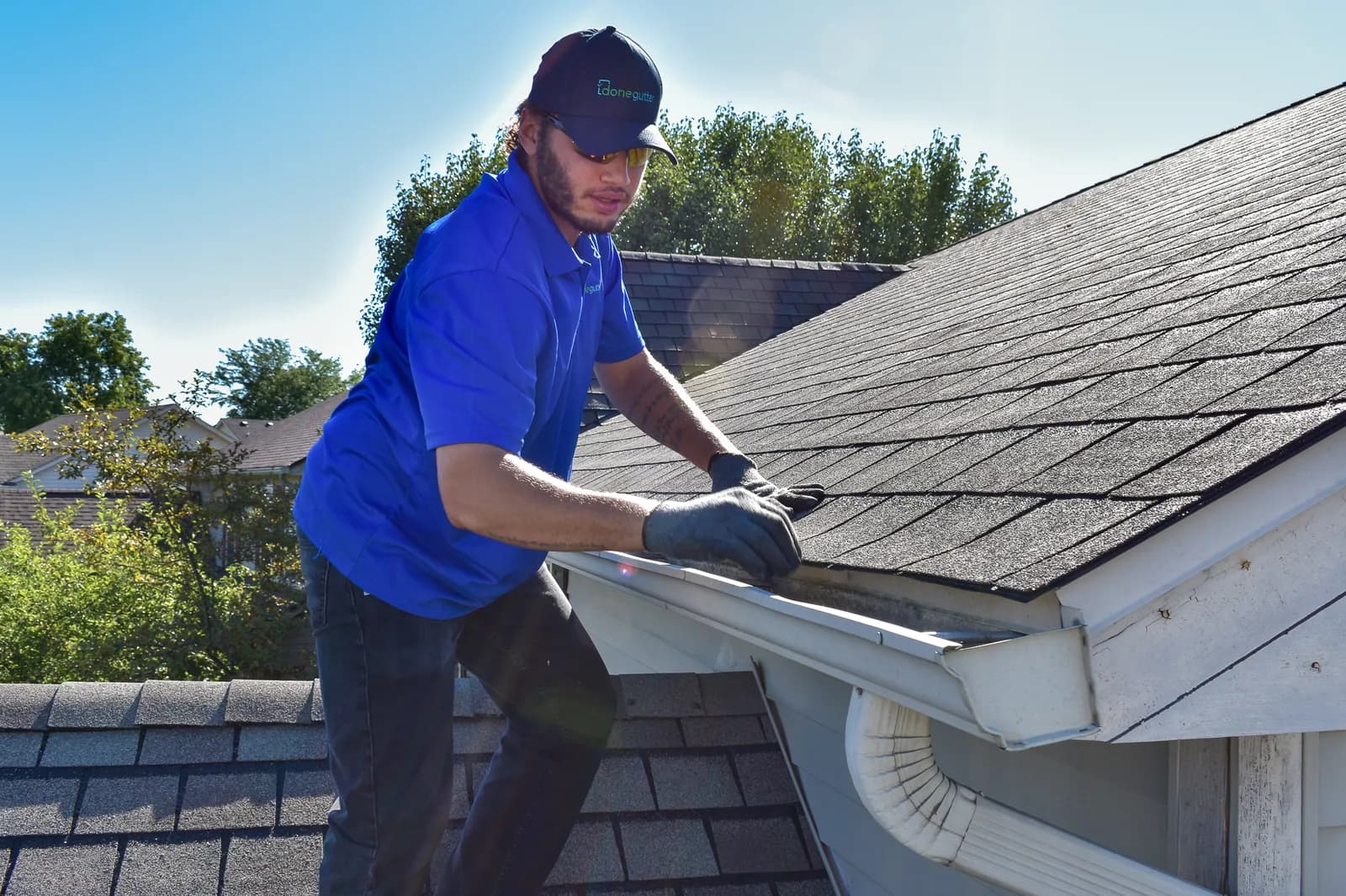 Technician cleaning gutter by hand on a walkable roof section
