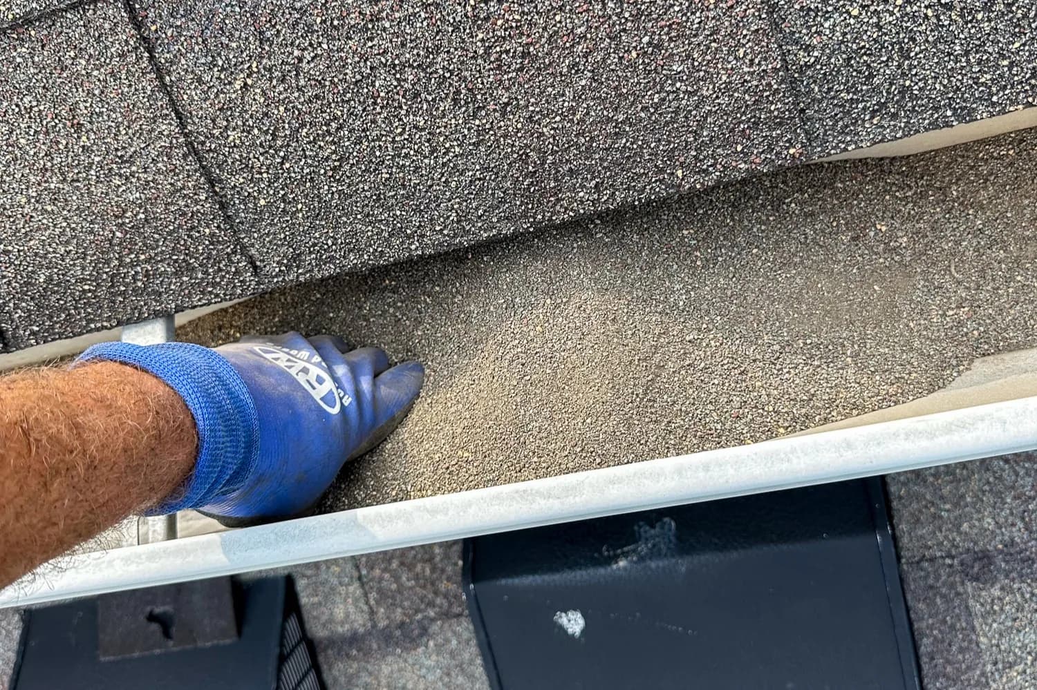 Close-up of shingle granule accumulation in gutter bottom